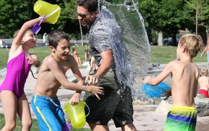 Kids and a dad playing in a Sacramento neighborhood splash park in summer