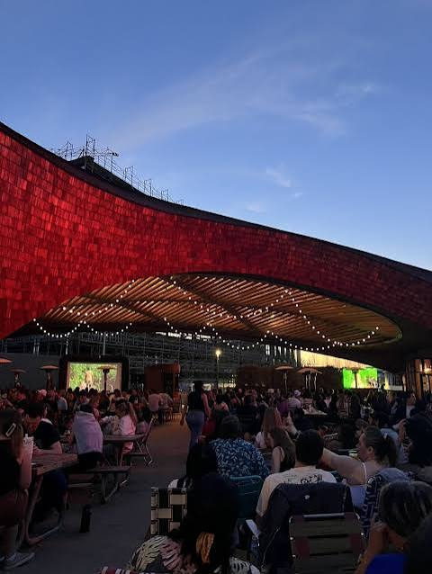 Crowd gathered under string lights at the Golden 1 Center plaza at sunset